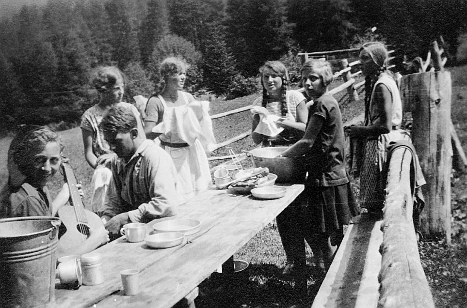 2. Sommerfahrt: Wandervögel waschen ihre Essnäpfe und das Geschirr in einer Schüssel auf dem Tisch im Freien - Ein Wandervogel Gitar