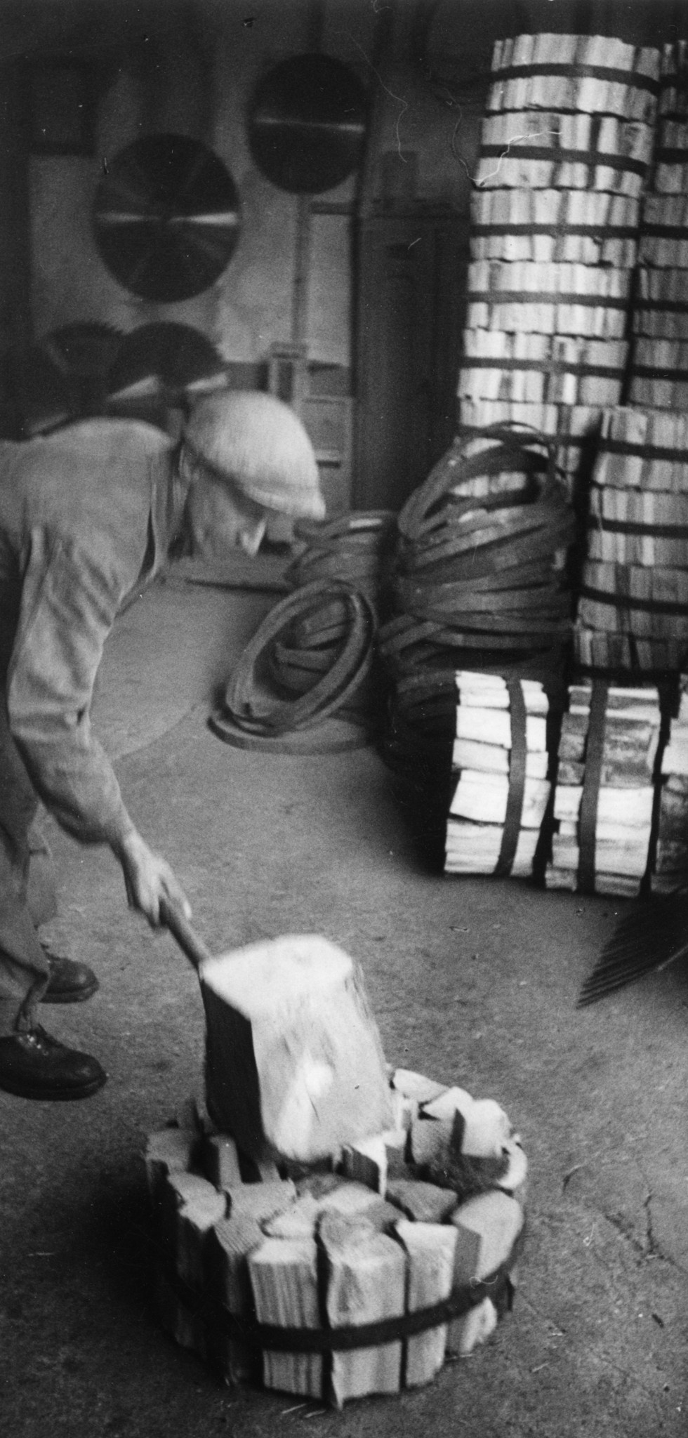 Kohle/Holz: Mann behandelt ein Bündel Holz mit dem Holzhammer