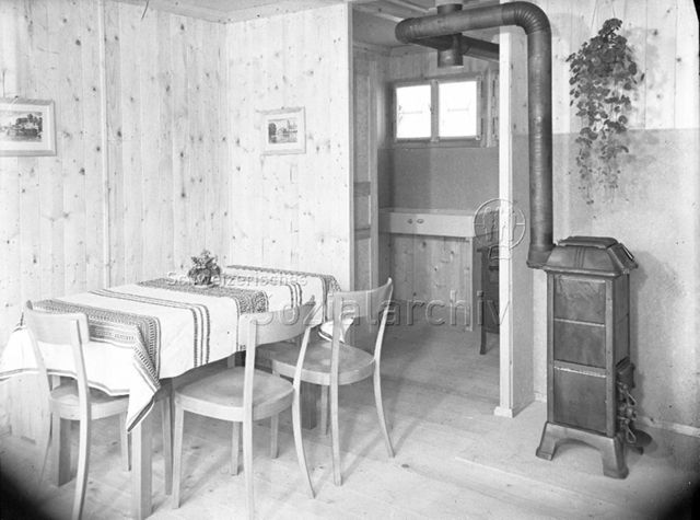 Wohnverhältnisse: Esstisch, Stühle, Ofen, Schüttstein (Spülbecken), um 1940