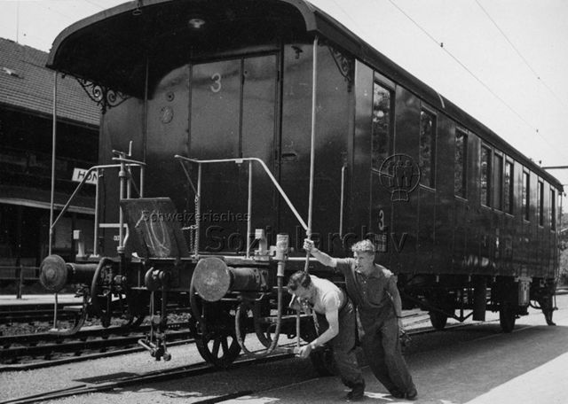 "Park im Grüene", Rüschlikon, Transport eines alten Zugwaggons - Zwei Arbeiter schieben den Waggon den Gleisen entlang; um 1960
