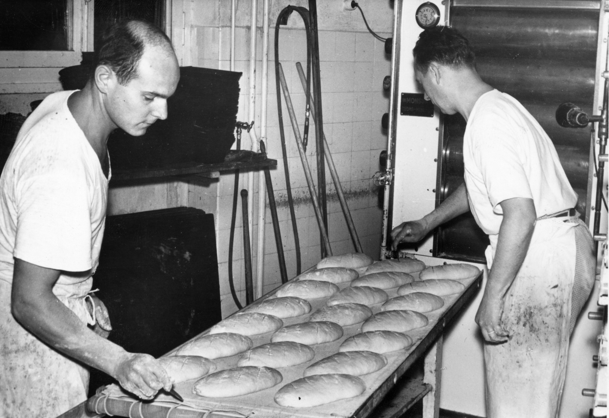 Zwei Männer schneiden Brotlaibe ein - in einer Bäckerei