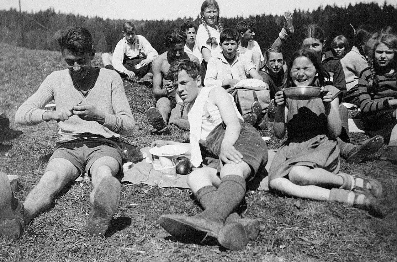 Wandervögel sitzen auf der Wiese bei einer Mahlzeit in Redlikon (zum Teil mit Essnäpfen) (April 1932)