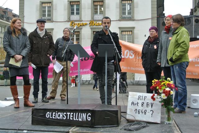 Kundgebung in Bern gegen die Familieninitiative der CVP (16.11.2013, Bern) – Sarg: Gleichstellung, daneben: "RIP - Art. 8 BV - 1848–?"; Alicia Parel (1. Person v. links), Rolf Trechsel (3. Person v. links); Banner des Pink Cross bzw. der LOS: "Keine Diskriminierung in unserer Verfassung, Finger weg! / Pas de discrimination dans notre constitution, bas les pattes!"