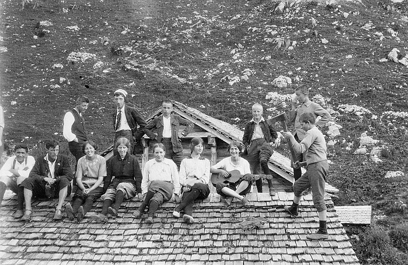 Gruppenporträt der Wandervögel auf dem Dach (Dach mit Schindeln) der Butzenalp-Wandervogelhütte - Ein Wandervogel Gitarre spielend,