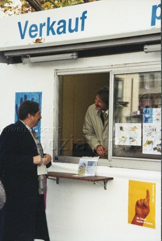 "Markenverkauf am Bellevue mit Zürcher Stadtpräsident Josef Estermann" - Herr Estermann im Verkaufsstand, davor steht ein weiterer Herr; 1997