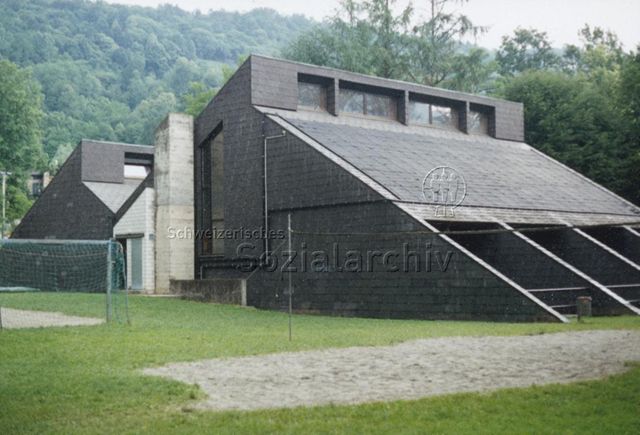 Bosco della Bella, Feriendorf für kinderreiche Familien - Aussenansicht eines Gebäudes, vorne Volleyballfeld und Fussballplatz; 1995