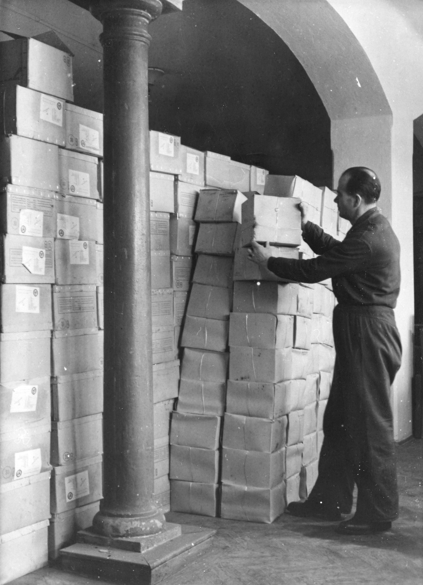 "Paketlager des Colis Suisse, 20. Jänner 1947"; ein Mann Pakete auftürmend