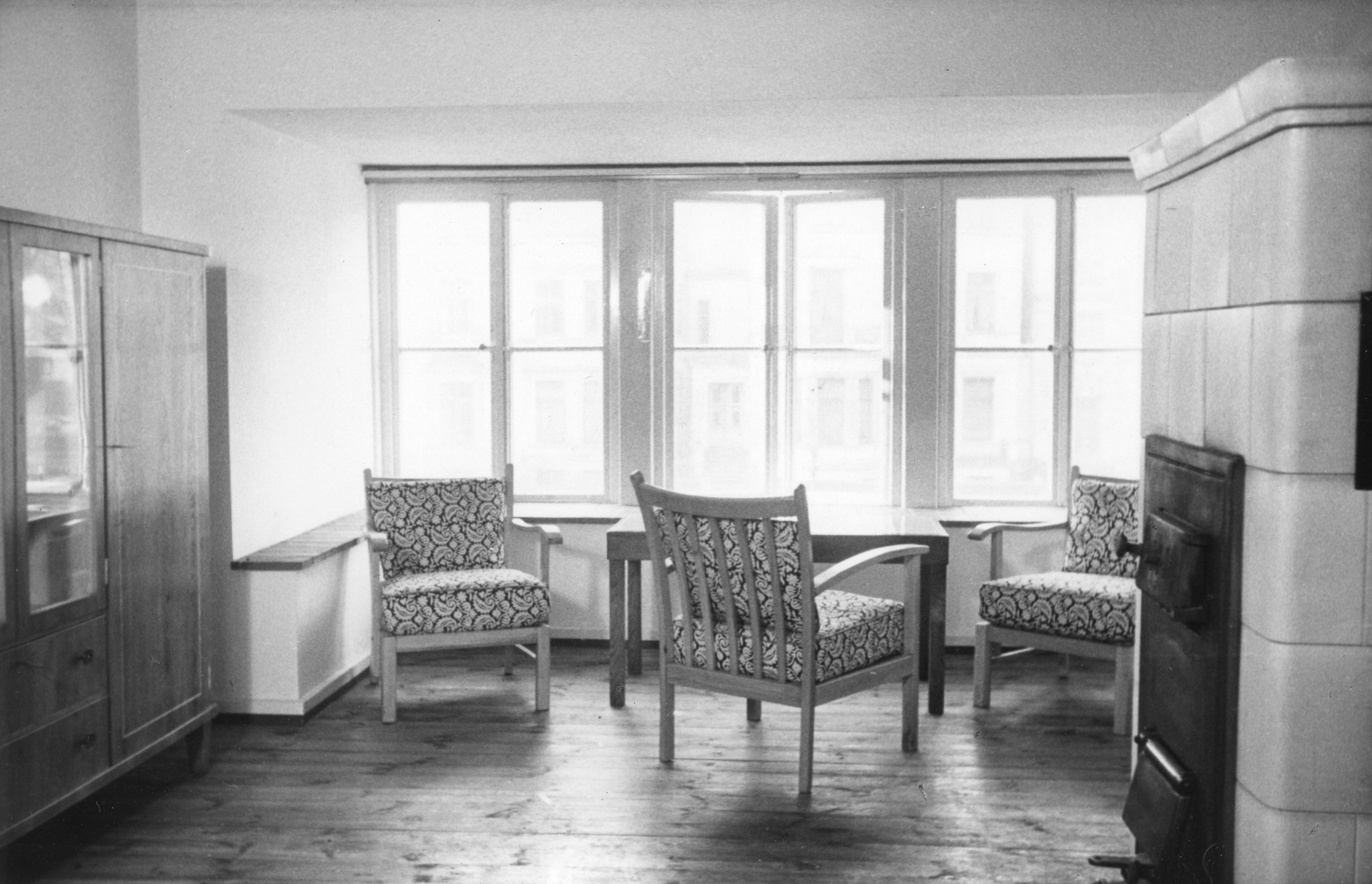 "Wohnung des Hausverwalters"; Blick in einen Wohnraum mit Sitzen, Tisch, Schrank und Kamin