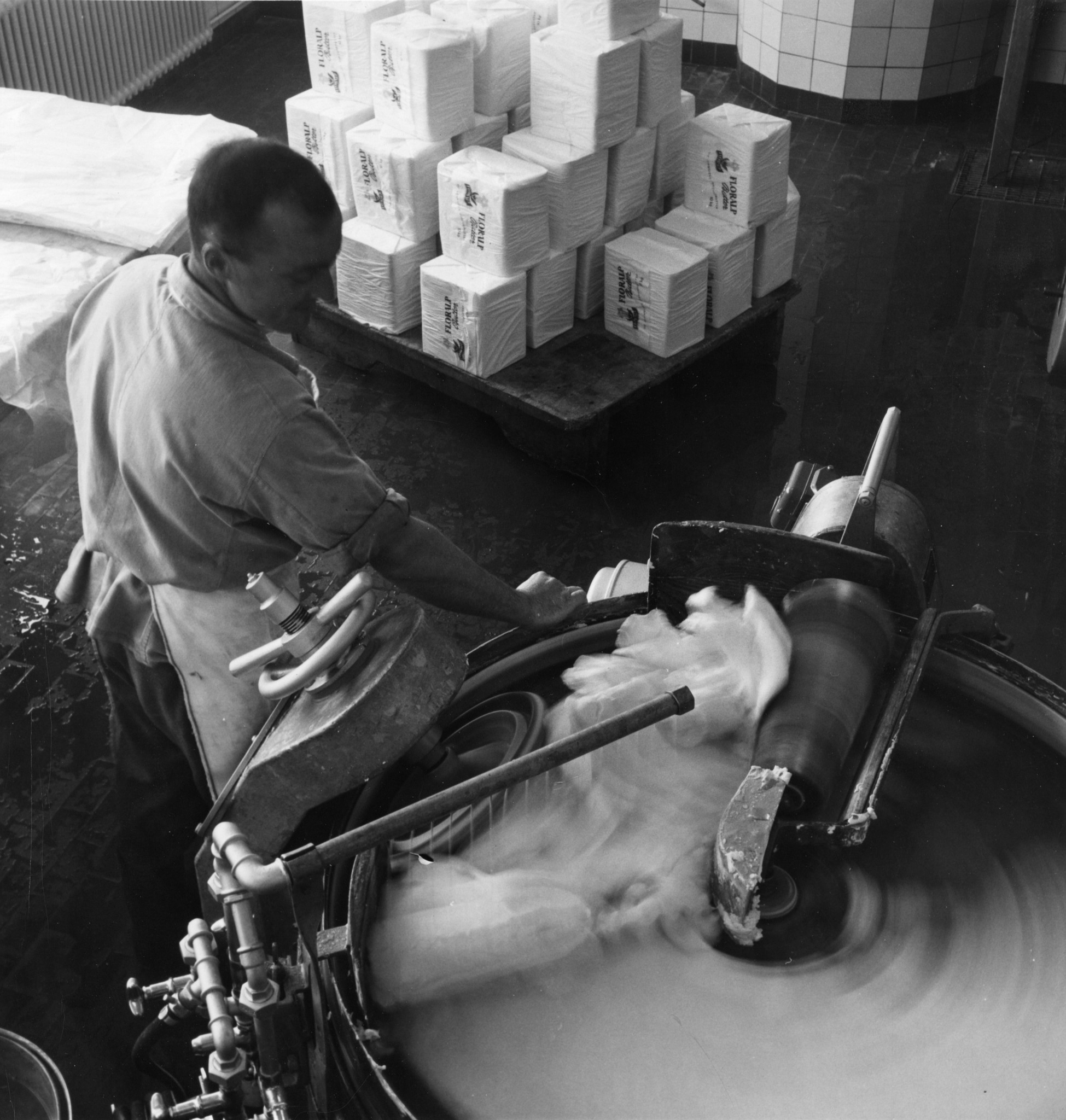 Mann stehend neben einer Produktionsanlage in der Lebensmittelindustrie, vermutlich Butter