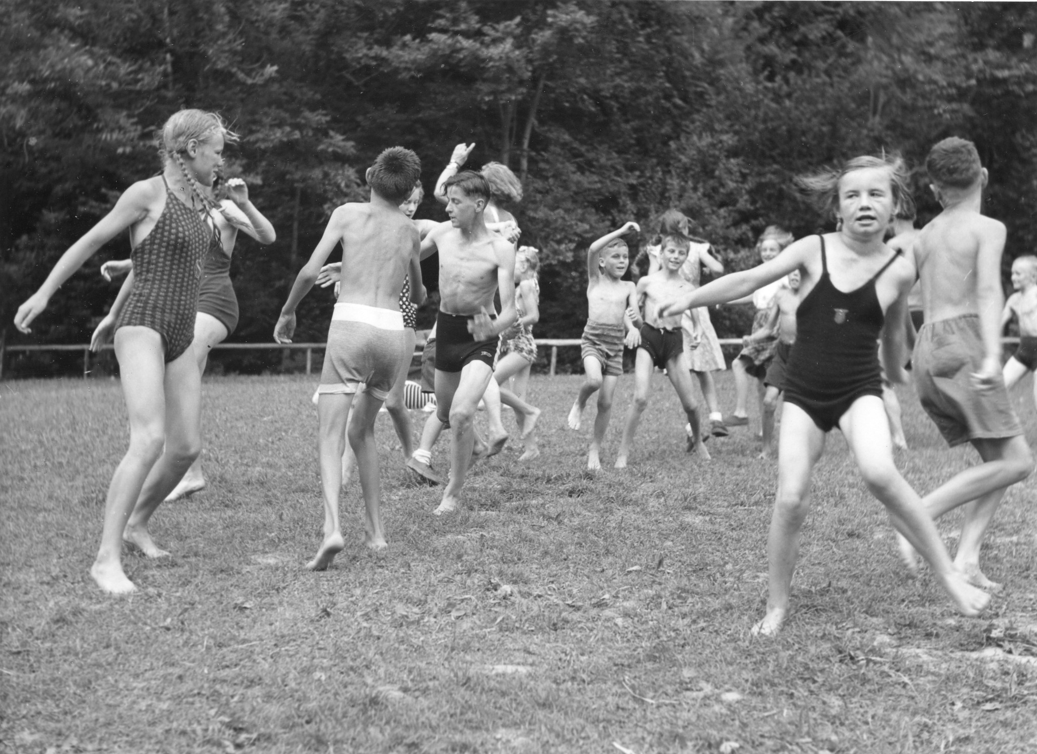 Ferienkolonie Landmark: Kinder springen in Badkleidung auf einer Wiese herum