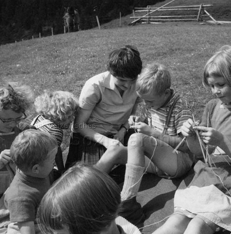 Praktikantinnenhilfe - Praktikantin lehrt Kinder das Stricken; um 1965