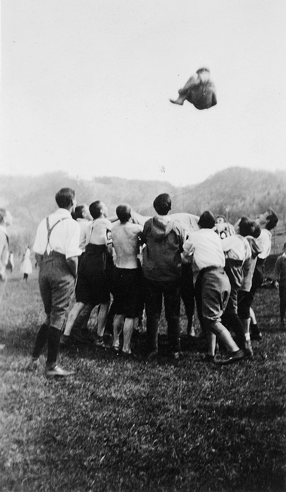 Prellen - Spiel im Freien: Wandervögel halten ein Tuch: In der Mitte des Tuches ein Wandervogel in die Luft springend (1920)