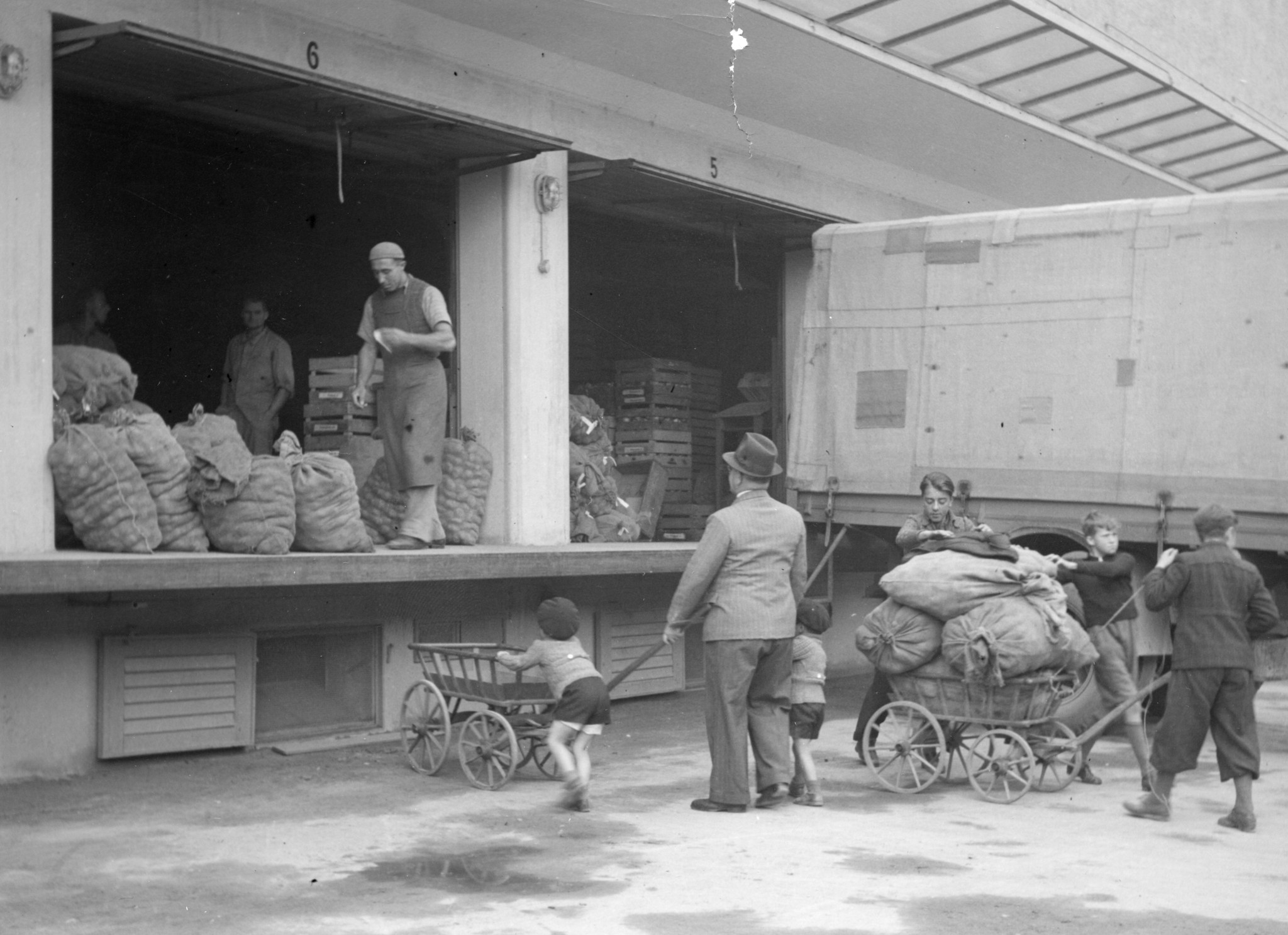 Lebensmittelausgabe ab Rampe: Käufer füllen ihre Leiterwagen mit Kartoffelsäcken
