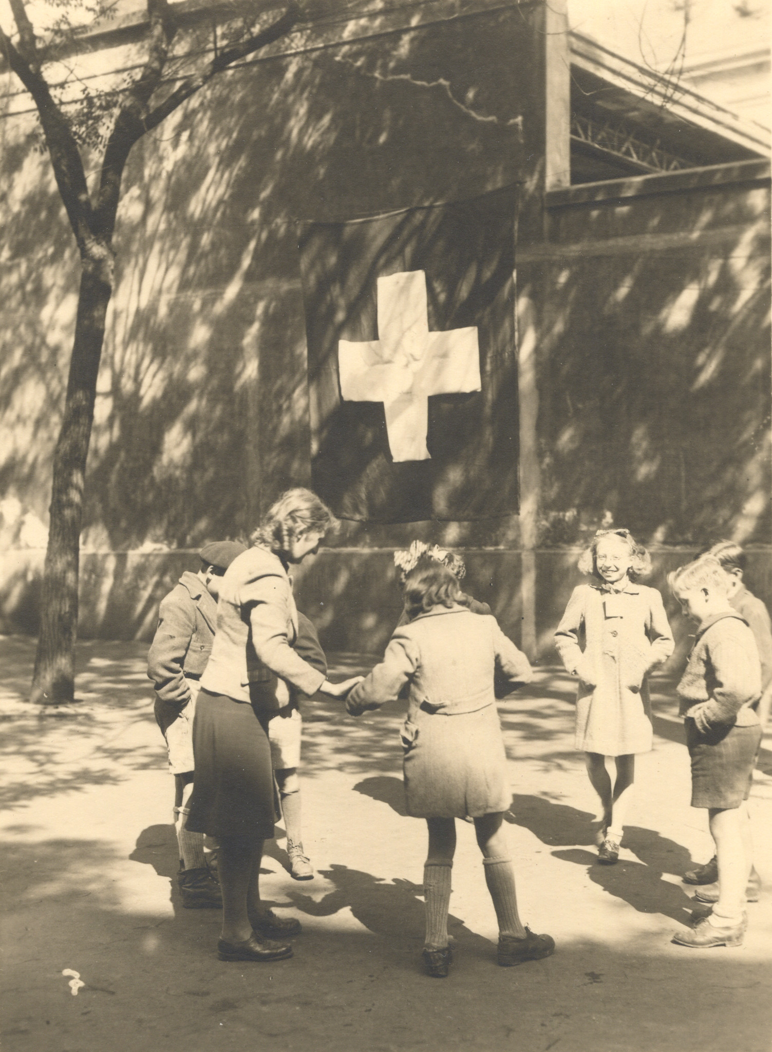 "Lyon, Herbst 1944, Kinder an einem Fest der SAH." Kinder beim Spielen, im Hintergrund Schweizer Fahne