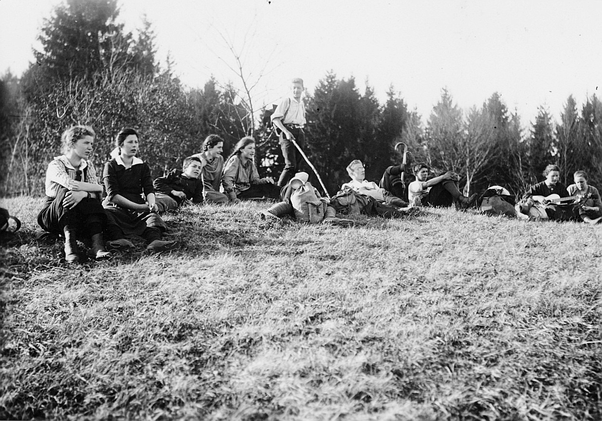 Wandervögel der Ortsgruppe Zürich-Altstadt sitzen auf der Wiese, ein Mädchen Gitarre spielend (1914)