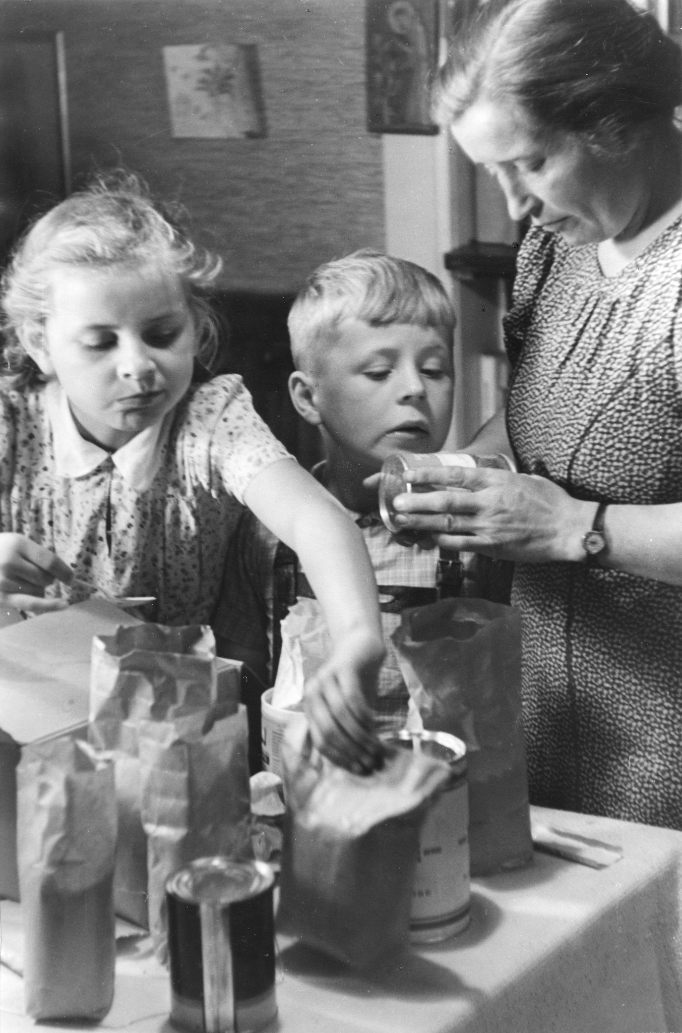 "Hamburg, Sommer 1948: ein Freipaket kommt an!"; Zwei Kinder und ihre Mutter betrachten die verschiedenen Geschenke