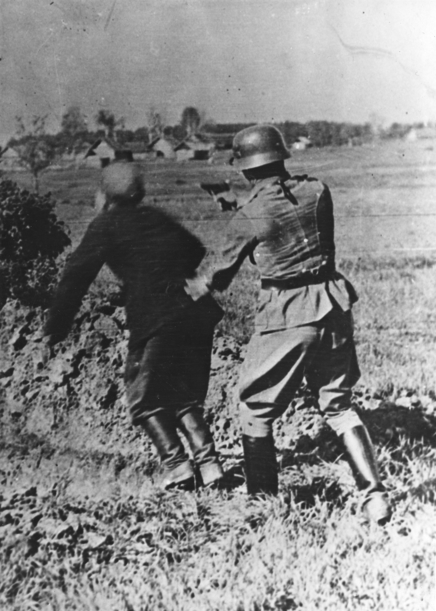 "Teresin [Terezin, Tschechien], "un SS-Mann  tue sa victime en la poussant vers la tombe", SS-Angehörige beim Erschiessen einer Person, während des Zweiten Weltkrieges
