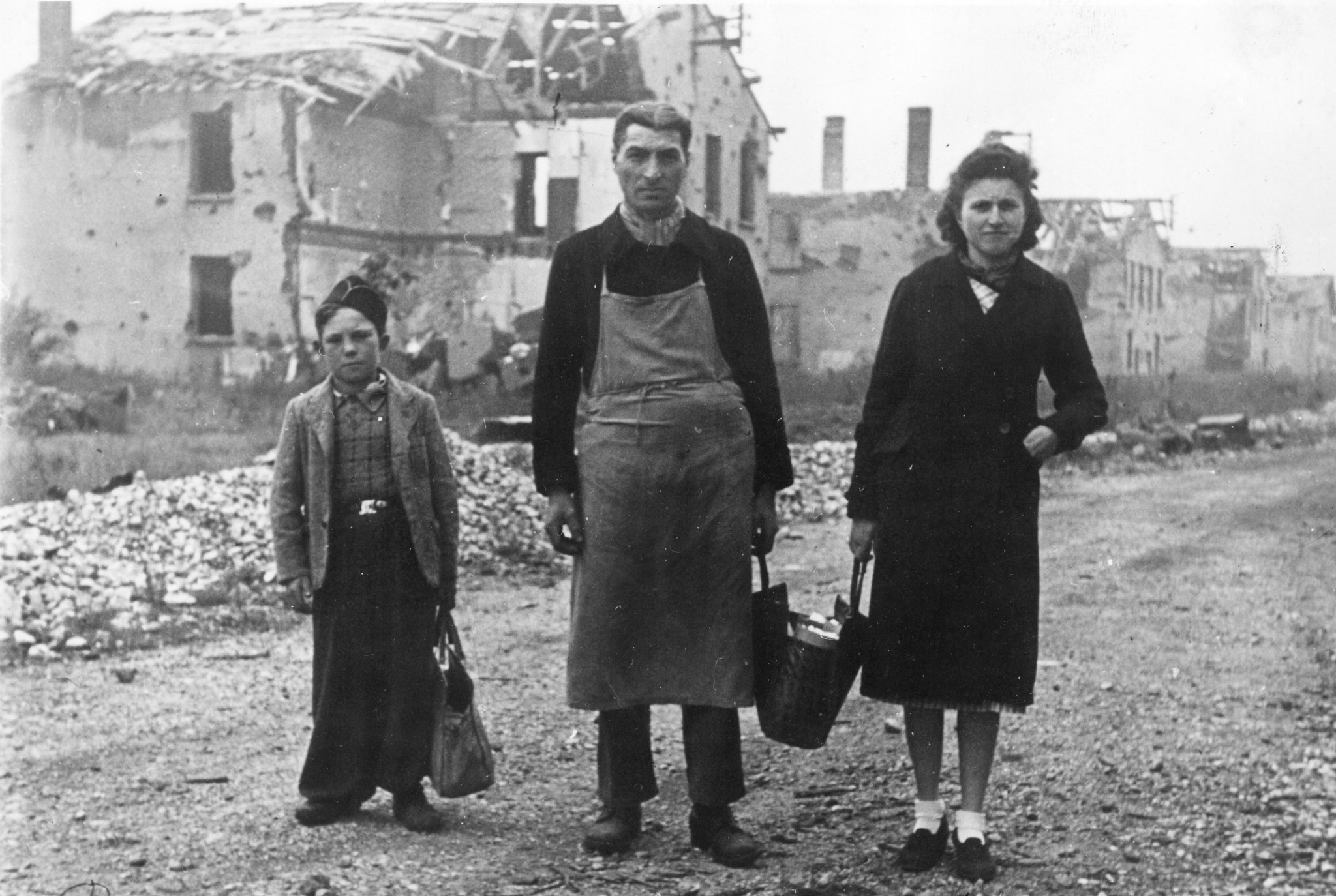 "Lyon, Oktober 1944. Der Heimweg im Arbeiterviertel der Stadt, das durch ein Bombardement zerstört wurde." Mann, Frau und Knabe kommen aus der Lebensmittelverteilung des SAH in den Berliet-Werke zurück.
