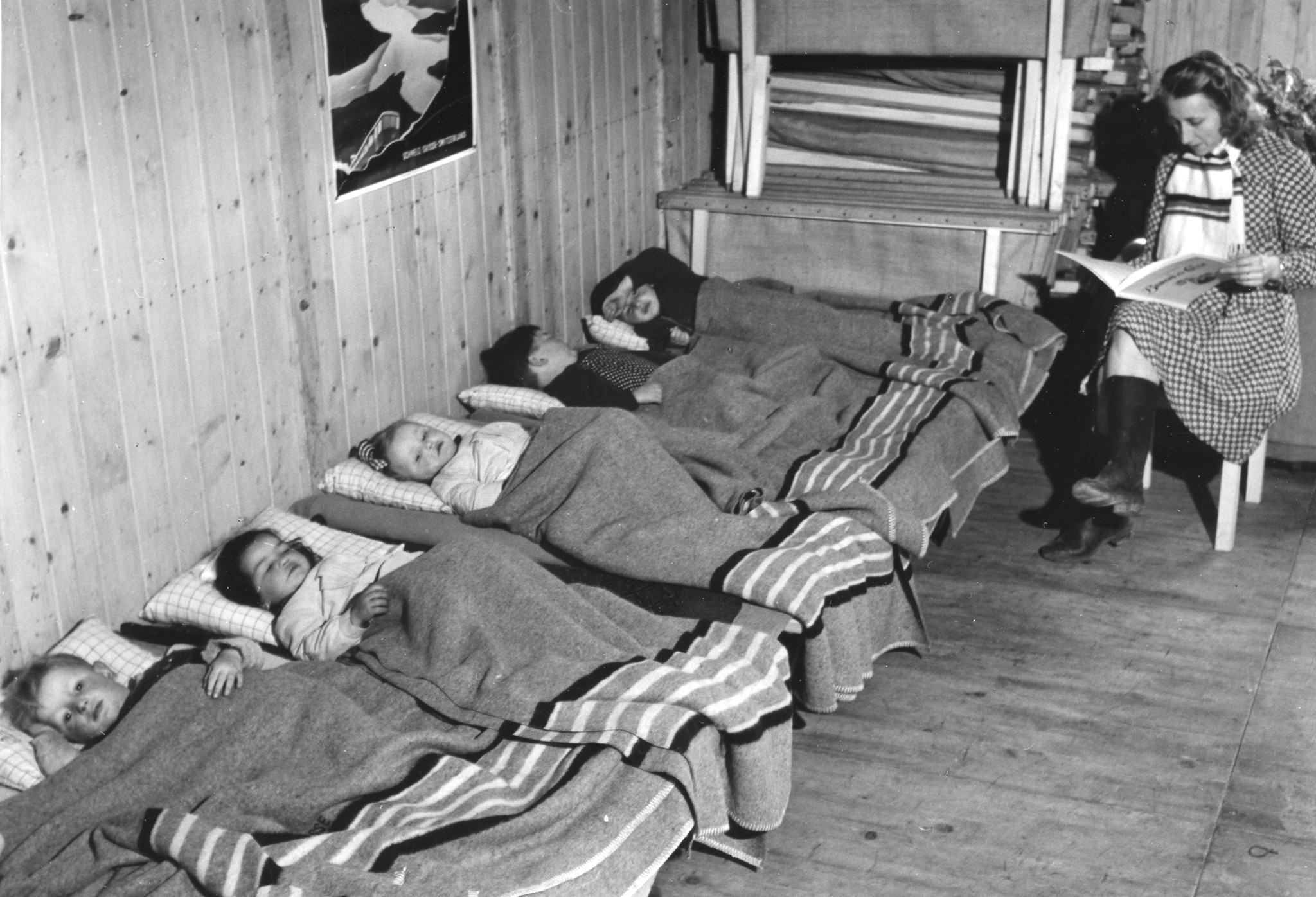Eine Betreuerin liest den Kleinkindern vor dem Einschlafen eine Gutenachtgeschichte vor
