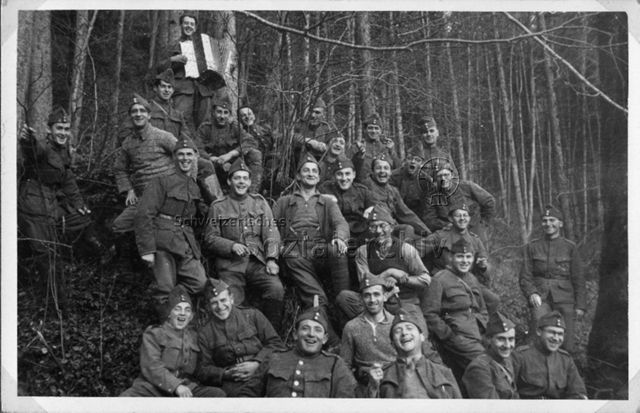 Album Alfred Brauchli, Teil 1/3: 699 Tage Aktivdienst 1939-1945 als Sanitätssoldat bei der Sanitätskompanie I/​7, Thurgau: Gruppenfoto von Soldaten in Uniform im Wald, einer spielt Handorgel