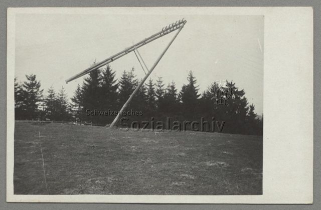 Schräg in der Landschaft stehender Mast einer Freiluftleitung, um 1910 (Kontext unbestimmt)
