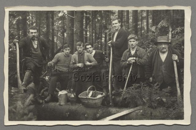 Holzfäller posieren im Wald mit Sägen, Äxten und Verpflegung, um 1930