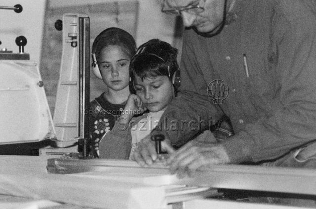 "Aktion 'Kinder besuchen ihre Eltern am Arbeitsplatz' - Aufnahmen in der 3. Primarschulklasse in Davos für die 'mitenand'-Sendung vom 03.11.1996 im SF DRS" - Zwei Kinder und der Vater an dessen Arbeitsplatz; 1996