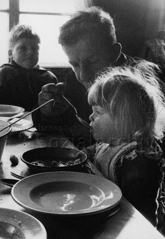 Praktikantinnenhilfe - Vater füttert Mädchen; um 1965
