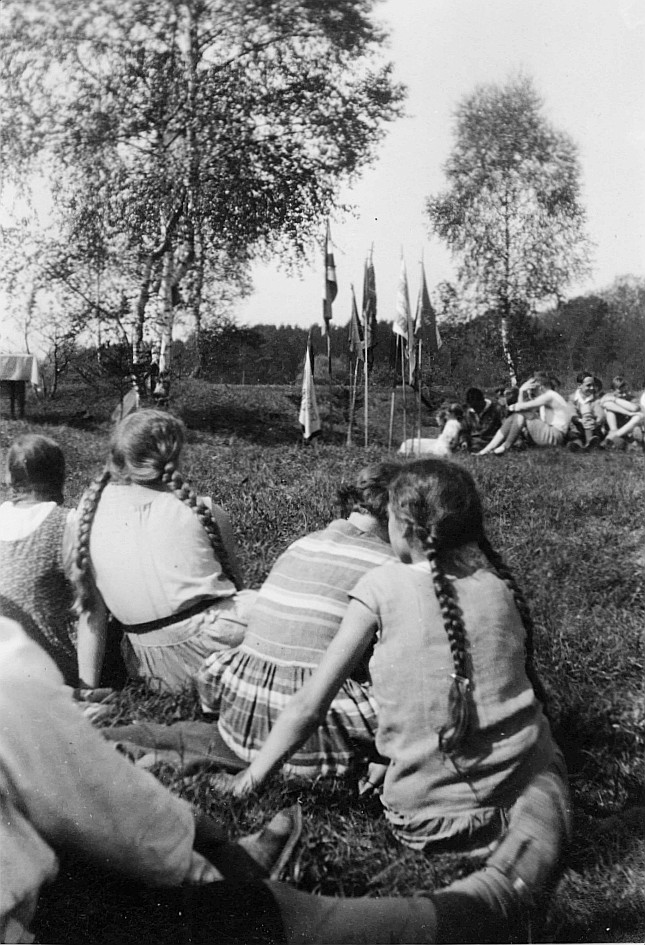 Wandervögel sitzen auf der Wiese während der Wandervogel-Landsgemeinde in Rümlang - Im Hintergrund sind die Fahnen (vermutlich der u