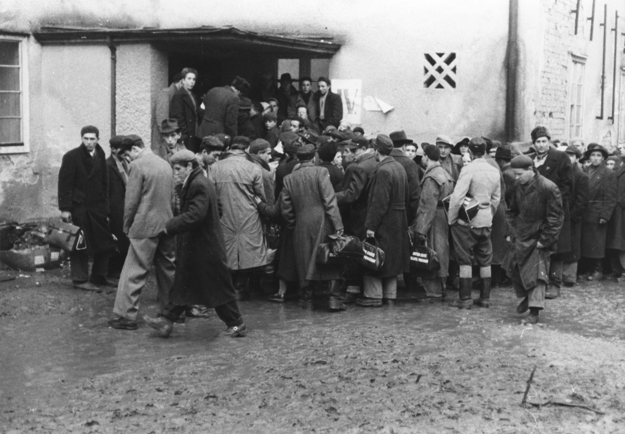 Männer warten vor einem Hauseingang des Eisenstaedt Lagers auf die Busse, die sie für die Migration nach England an den Flughafen bringen sollen