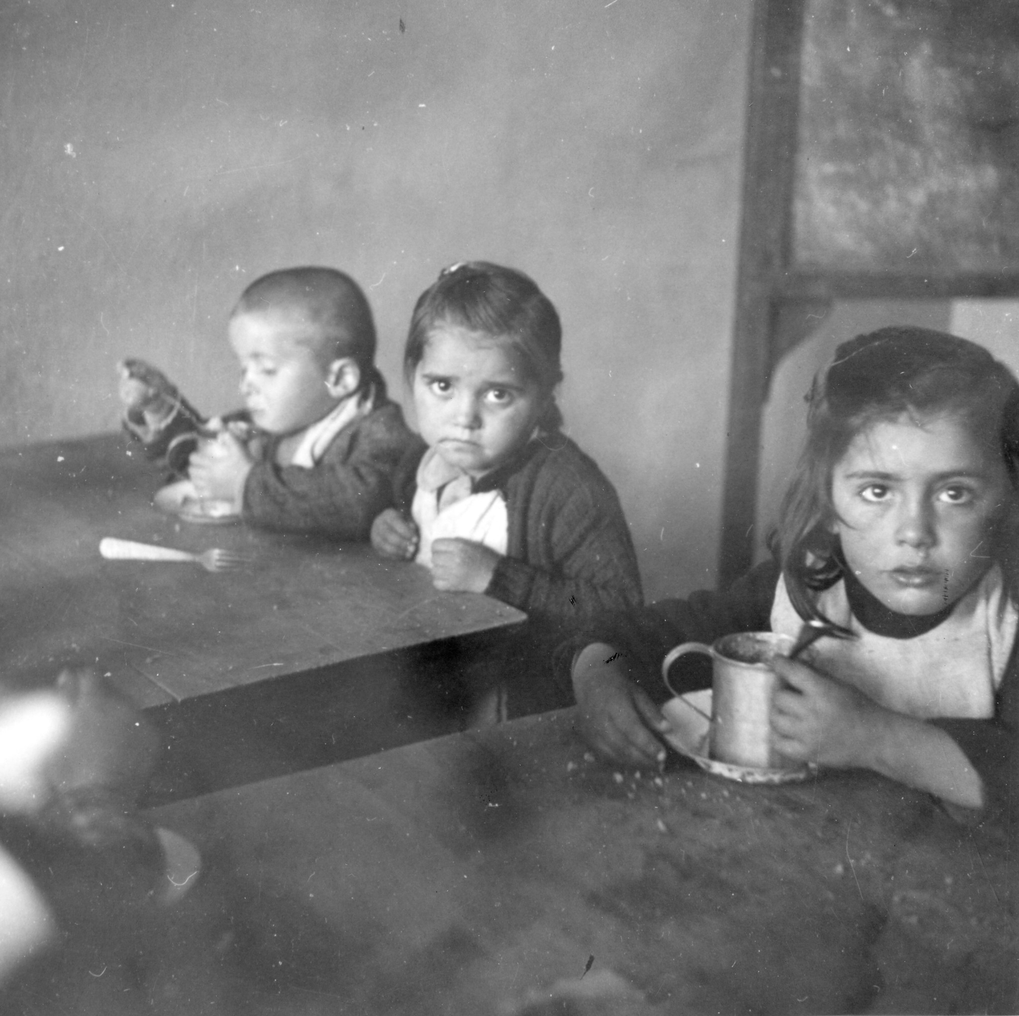 Kinder sitzen an Tischen und essen