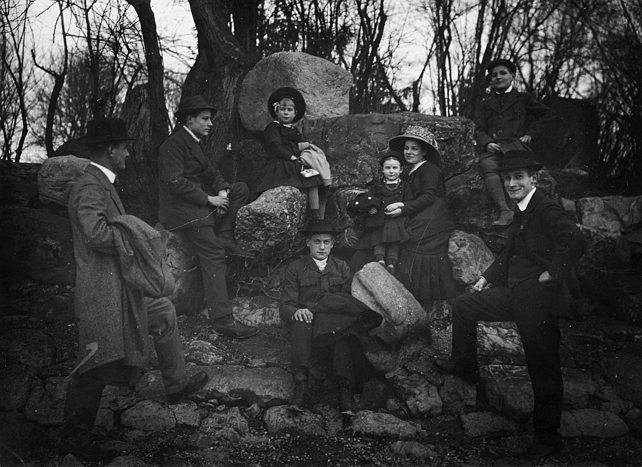 Römmer [Römer] und seine Geschwister - Erwachsene und Kinder sitzen auf Steinen in einem Wald (vermutlich aus einer privaten Fotosam