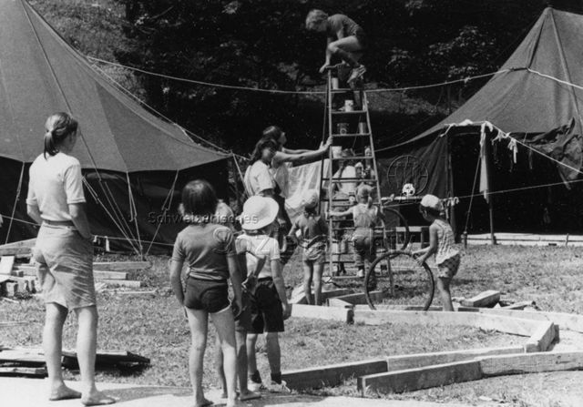Kinder spielen im Parcours, beaufsichtigt von Erwachsenen; um 1980
