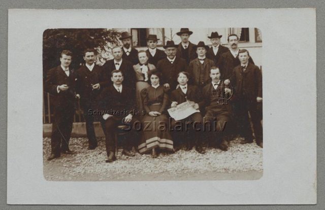 Gruppenbild "Kostbude", junger Mann mit Zeitung "Le peuple", Poststempel: 1909 (Kontext unbestimmt)