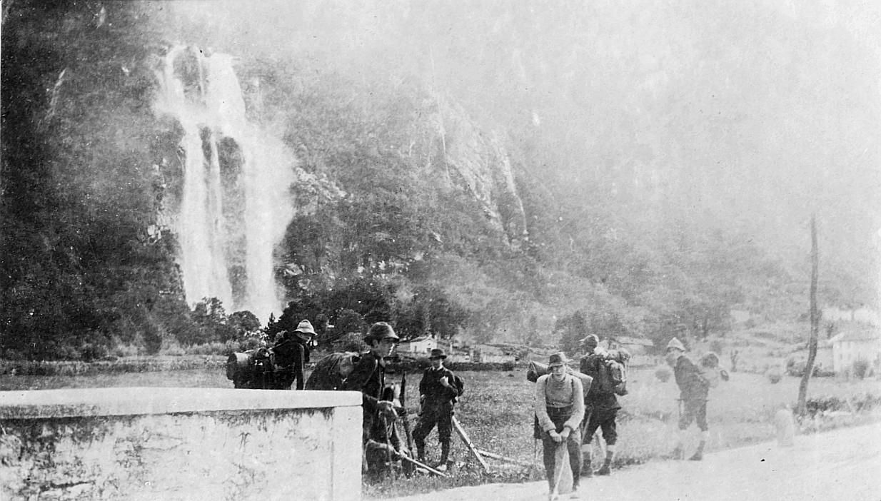 Wandervögel (mit Rücksäcken) auf Tour im Bergell - Im Hintergrund ist ein Wasserfall sichtbar (1912)