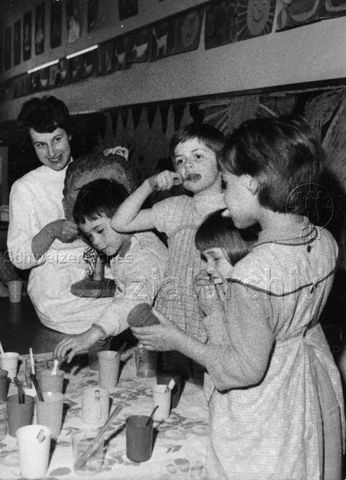 "Seminar für Jugend-Zahnpflege, veranstaltet durch Schweizerische Zahnärztegesellschaft" - Kinder beim Zähneputzen, hinten zeigt eine Frau mithilfe einer Puppe wie es geht; um 1960