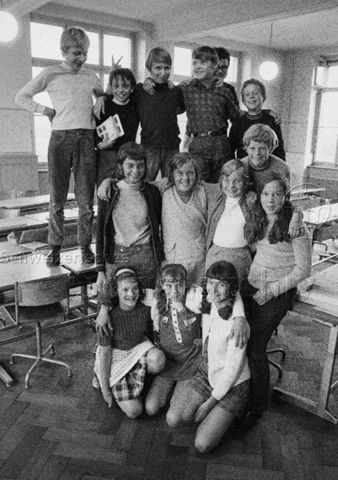 "Schule" - Kinder beim Gruppenfoto im Schulzimmer, die hinterste Reihe steht auf den Tischen; 1970
