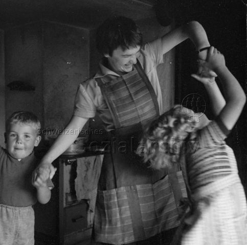 Praktikantinnenhilfe - Praktikantin spielt mit zwei Kindern; um 1965
