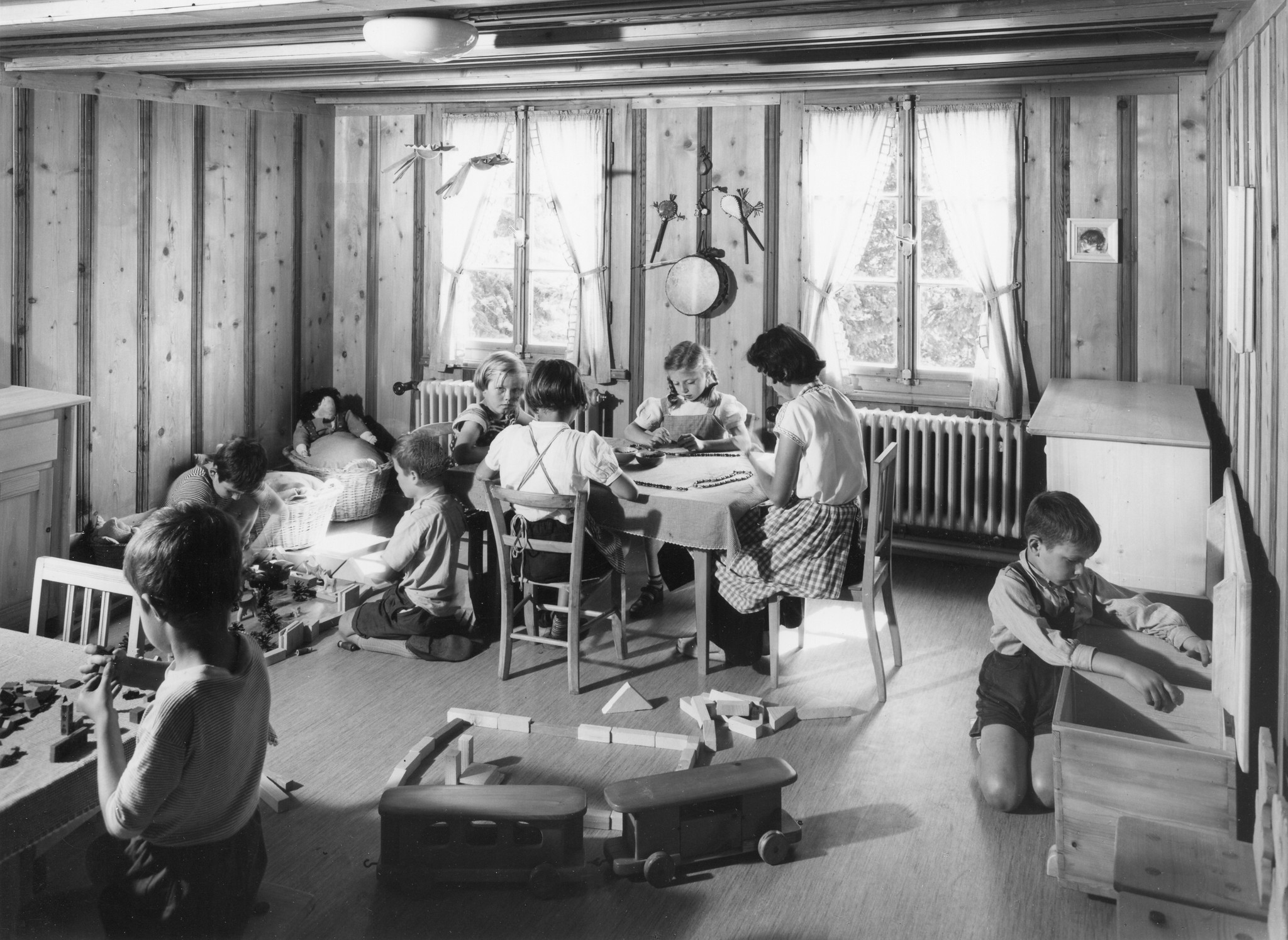 Kinder spielen in einem Zimmer unter Aufsicht einer Erwachsenen