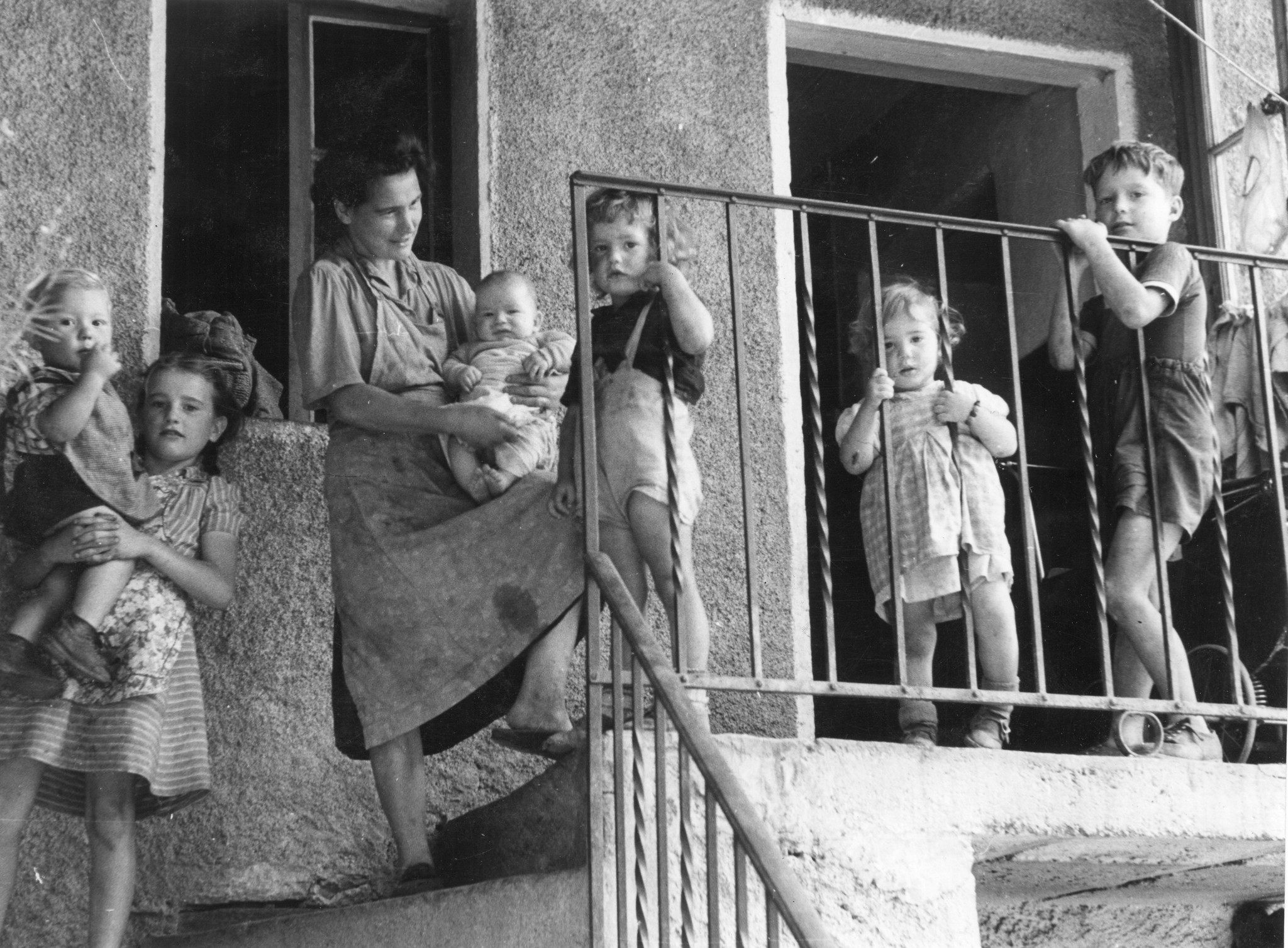 Eine Mutter steht mit ihren Kindern auf der Treppe vor ihrem Haus